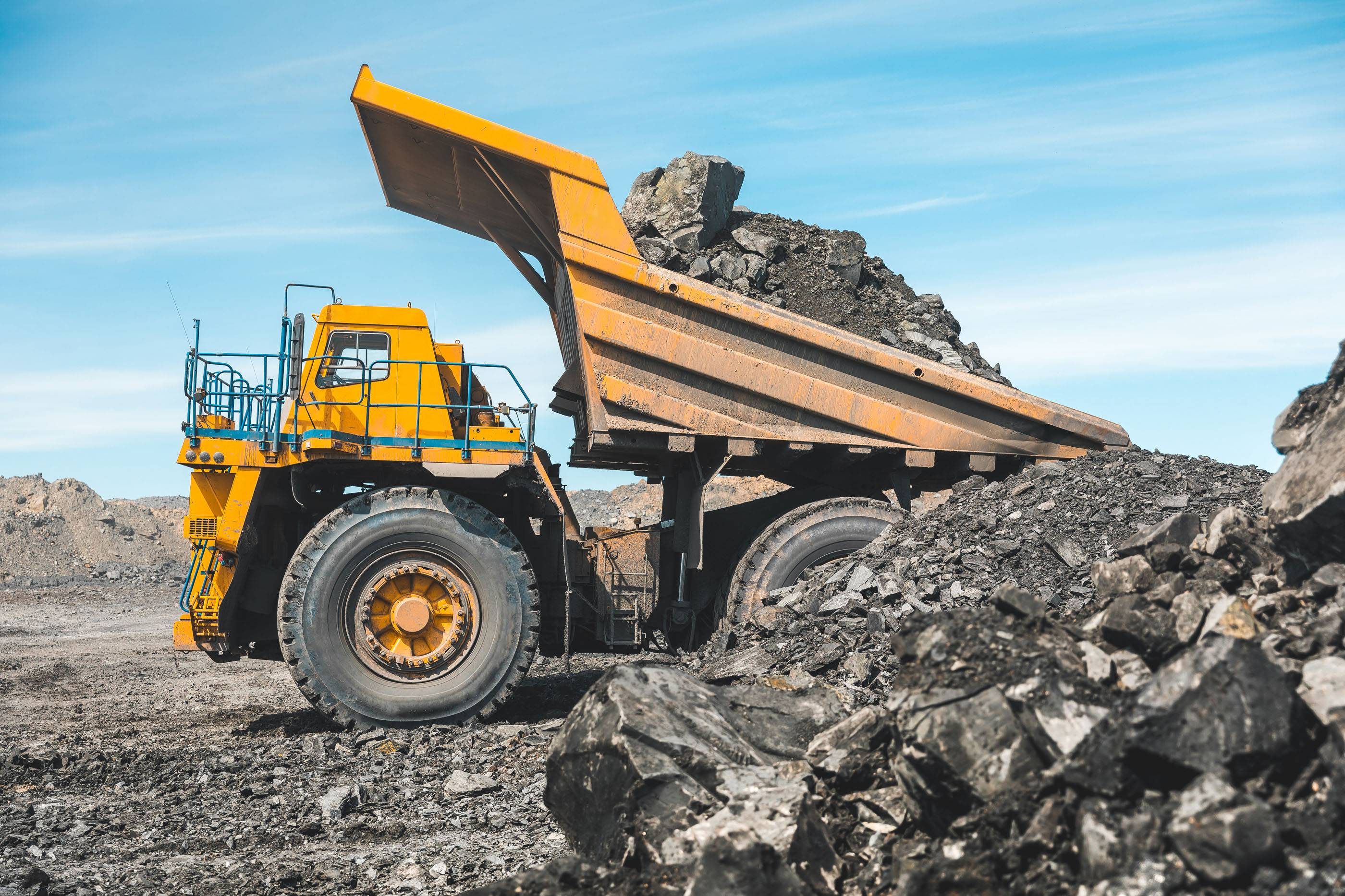 Большой карьерный самосвал. Загрузка породы в самосвал. Погрузка угля в кузов грузовика. Карьерная техника для транспортировки угля из разреза. Добыча полезных ископаемых