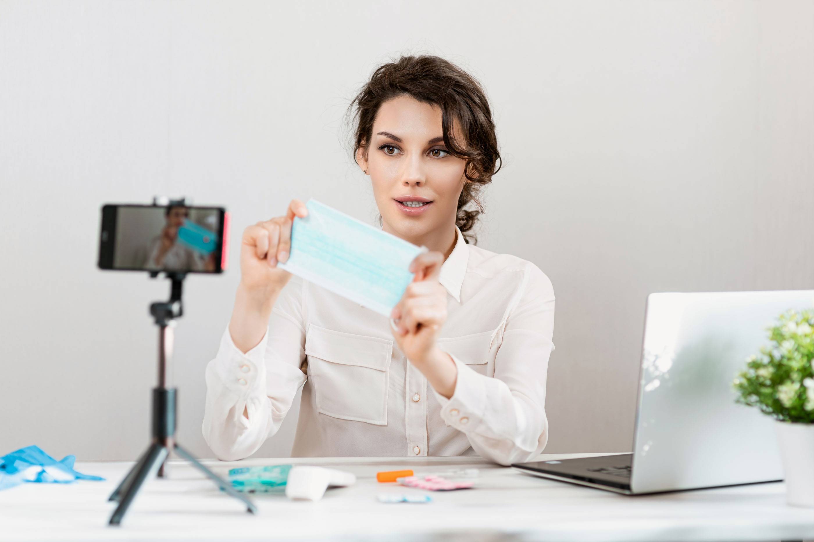 Девушка-блогер в медицинской маске рассказывает о коронавирусе. Женщина записывает видеоблог о том, как защитить себя от 2019-nCov. Блогер рассказывает о MERS-CoV, использовании спиртовых салфеток и термометра.