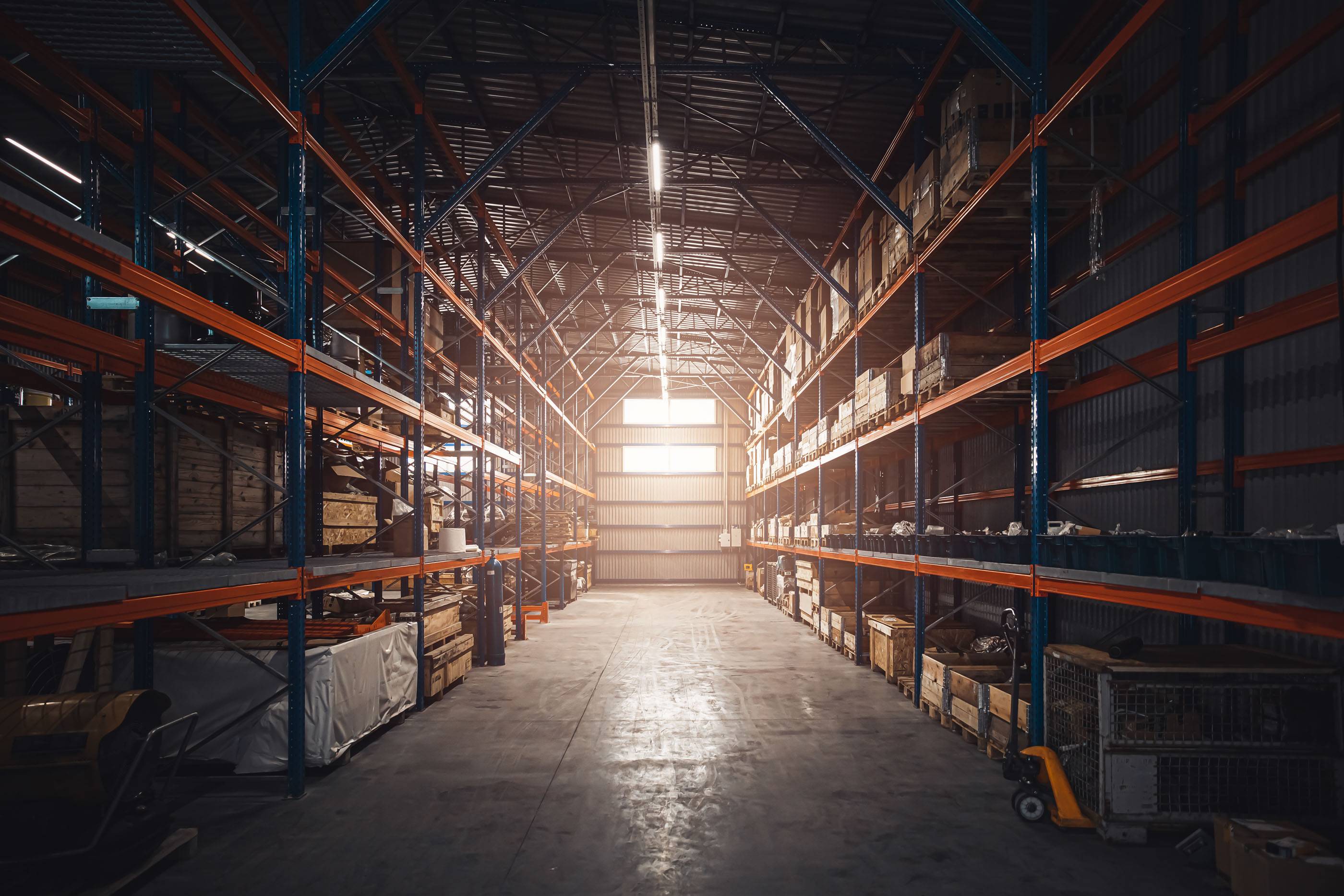 Интерьер современного склада розничного магазина. Большой промышленный склад. Высокие стеллажи заполнены коробками и контейнерами. Ангар промышленно-логистической компании. Полки с разнообразными коробками.