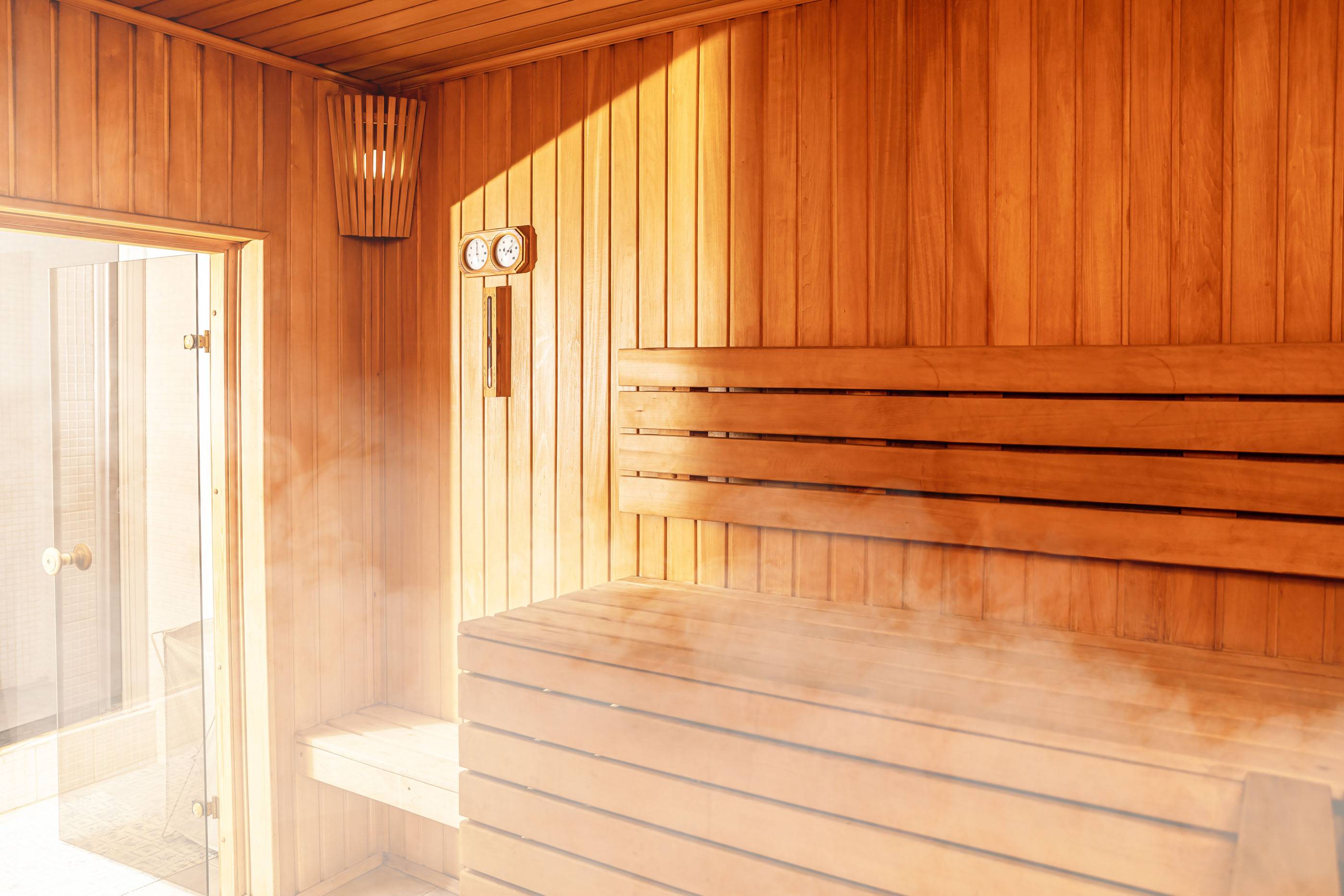 Интерьер финской сауны, классическая деревянная сауна с горячим паром. Русская баня. Отдых в горячей сауне с паром. Деревянный интерьер бани, деревянные скамьи и шезлонги, аксессуары для сауны, спа-комплекс.