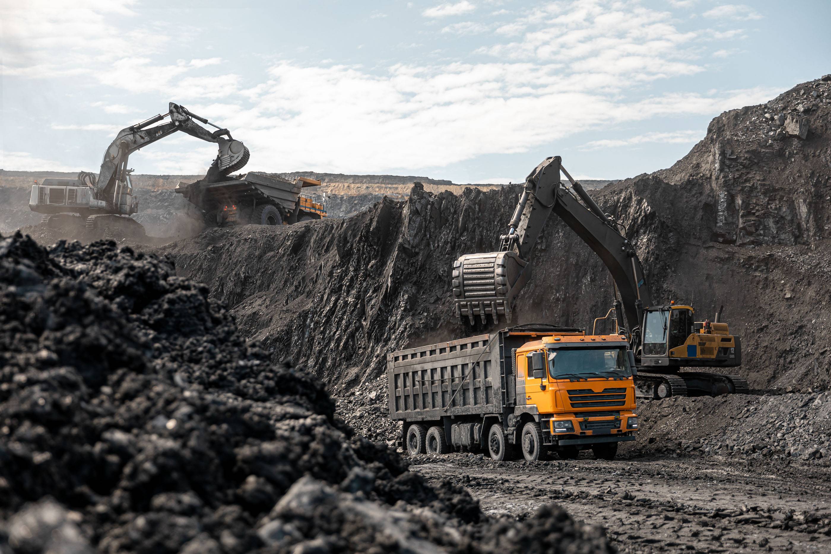 Большой карьерный самосвал и экскаватор. Крупная техника на угольном разрезе. Погрузка угля в кузов. Добыча полезных ископаемых. Транспортировка угля из разреза.