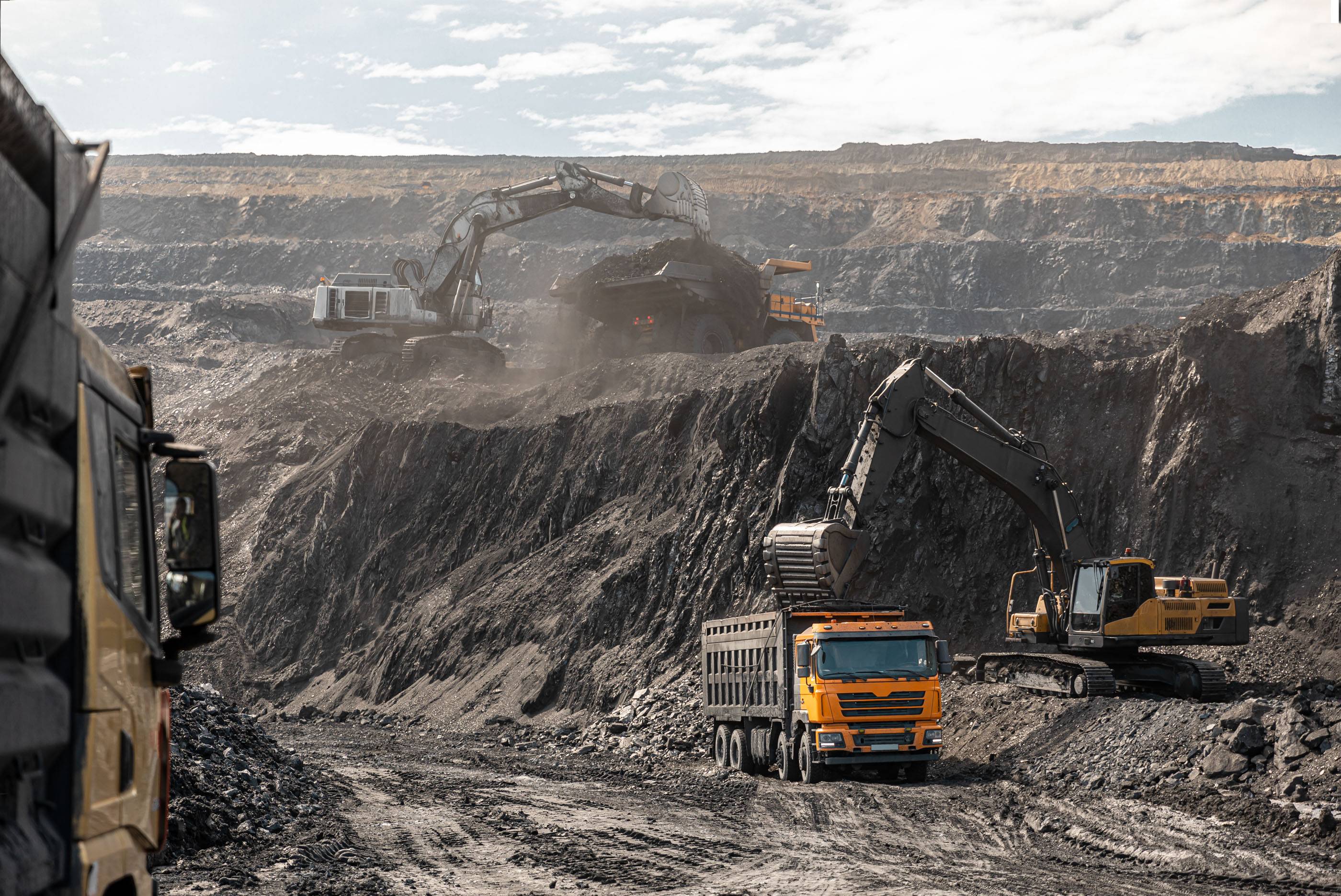 Большой карьерный самосвал и экскаватор. Крупная техника на угольном разрезе. Погрузка угля в кузов. Добыча полезных ископаемых. Транспортировка угля из разреза.