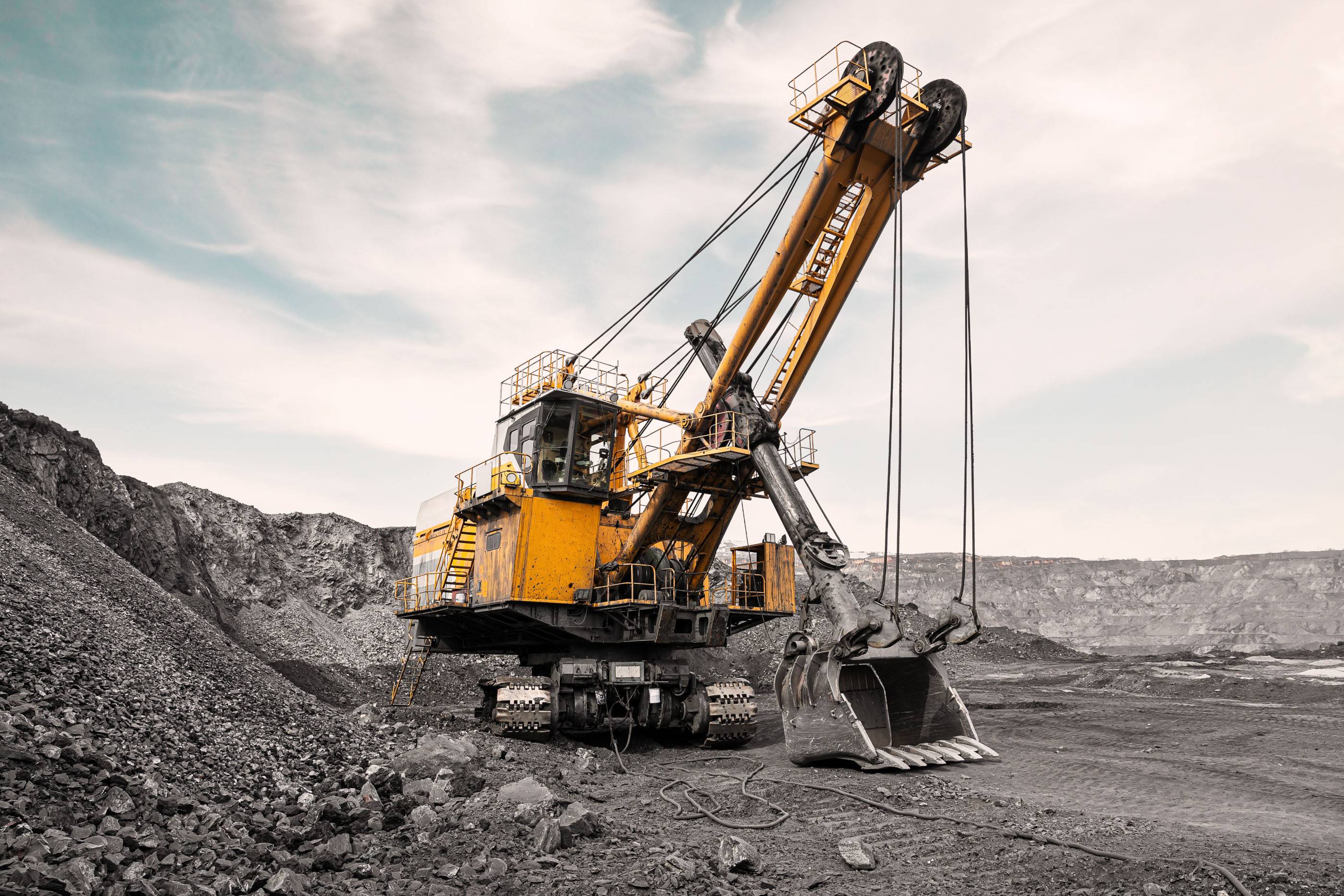 Большой карьерный экскаватор. Крупная желтая выемочная машина на объекте. Погрузка угля в кузов грузовика. Добыча полезных ископаемых. Карьерная техника для транспортировки угля из разреза