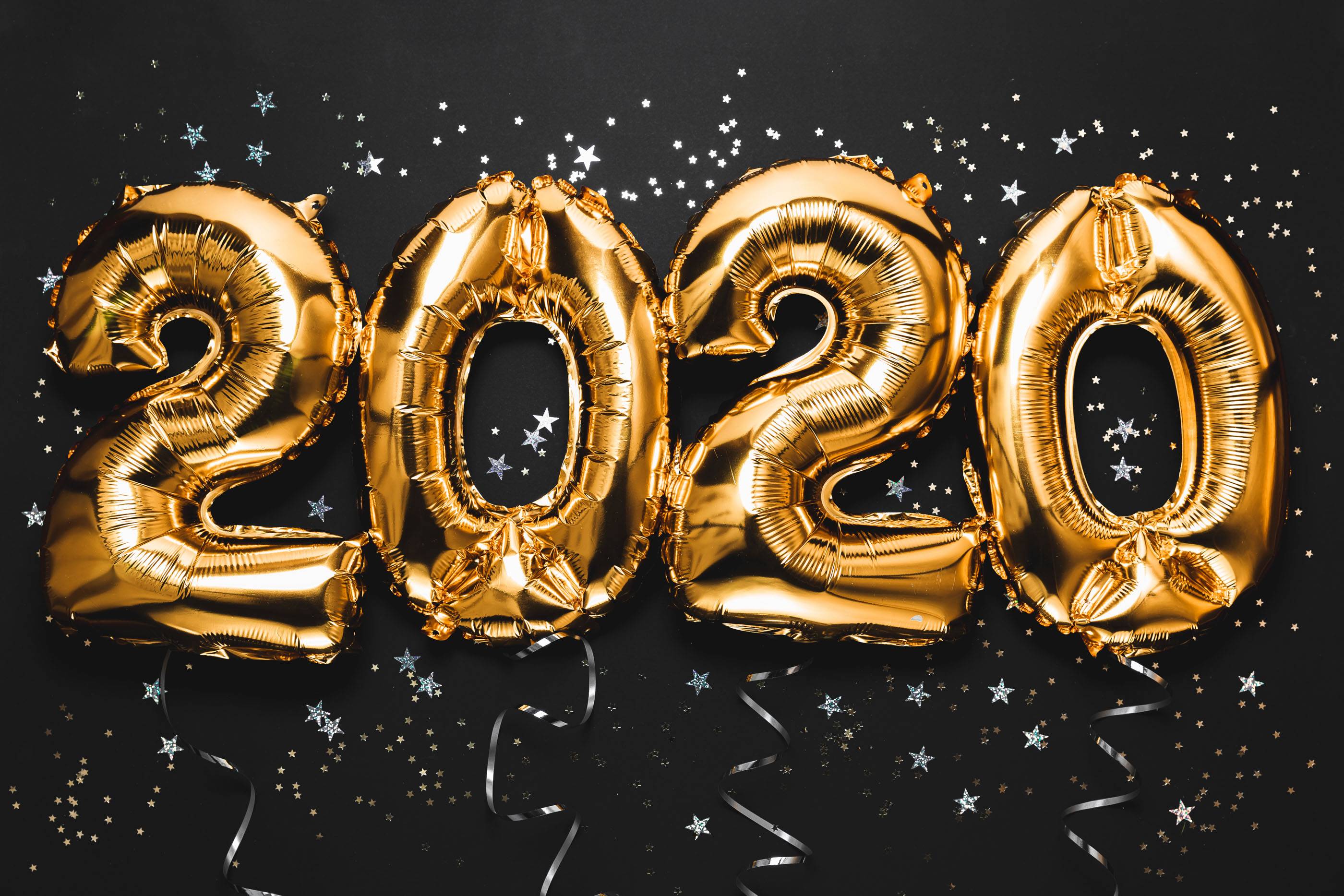 Празднование Нового 2020 года. Яркие золотые цифры, новогодние шары с блестками на темном фоне. Рождественское и новогоднее торжество. Фольгированные цифры 2020 и конфетти