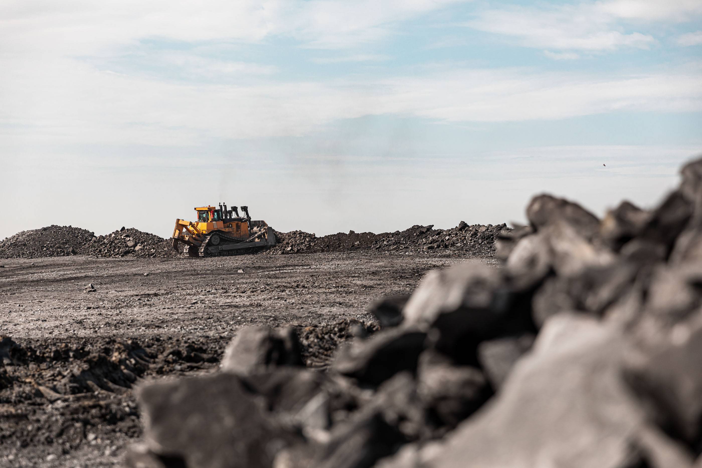 Большой карьерный самосвал. Большой желтый горный грузовик на рабочей площадке. Загрузка угля в кузов самосвала. Добыча полезных ископаемых. Карьерная техника для транспортировки угля из разреза.