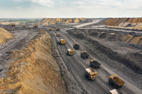 Большой карьерный самосвал. Большой желтый горный грузовик на рабочей площадке. Загрузка угля в кузов самосвала. Добыча полезных ископаемых. Карьерная техника для транспортировки угля из разреза.