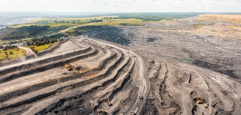 Панорамный вид с воздуха на угольный разрез. Открытая разработка месторождений, большой желтый карьерный самосвал. Добыча антрацита открытым способом. Погрузка породы в грузовики.