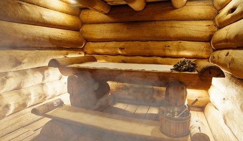 Русская баня. Отдых в горячей сауне с паром. Интерьер финской сауны, классическая деревянная парная. Деревянная отделка, скамейки и аксессуары для сауны, спа-комплекс.