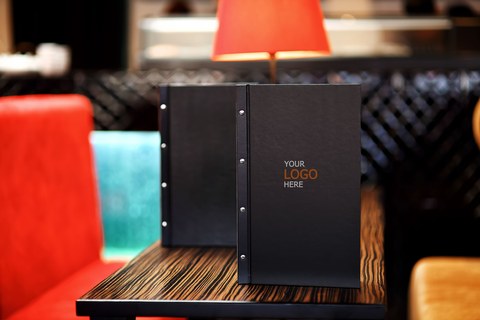 Стол в суши-ресторане: черное меню, деревянные подносы, свежие роллы, васаби, имбирь и палочки. Японская кухня и подача блюд. Современный интерьер ресторана.