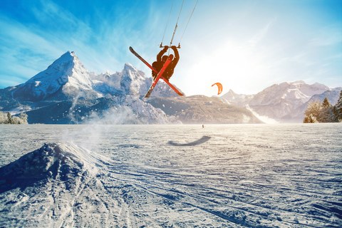 Молодые люди, катающиеся на лыжах по замерзшему озеру в горах в лучах восходящего солнца, зимой, в отпуске