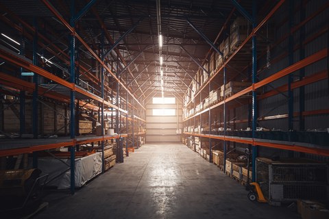 Интерьер современного склада розничного магазина. Большой промышленный склад. Высокие стеллажи заполнены коробками и контейнерами. Ангар промышленно-логистической компании. Полки с разнообразными коробками.