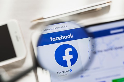 Калифорния, США — 7 марта 2019 г.: главная страница официального сайта Facebook под увеличительным стеклом. Концепт Facebook: логотип соцсети на экране планшета и смартфона