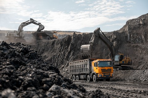 Большой карьерный самосвал и экскаватор. Крупная техника на угольном разрезе. Погрузка угля в кузов. Добыча полезных ископаемых. Транспортировка угля из разреза.