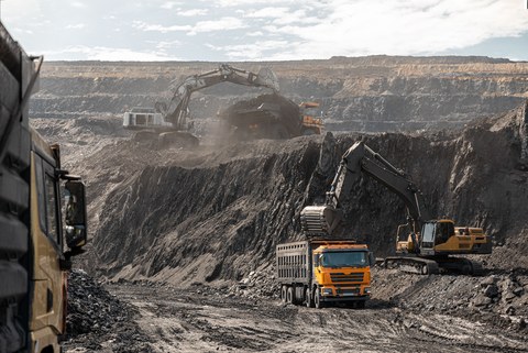 Большой карьерный самосвал и экскаватор. Крупная техника на угольном разрезе. Погрузка угля в кузов. Добыча полезных ископаемых. Транспортировка угля из разреза.