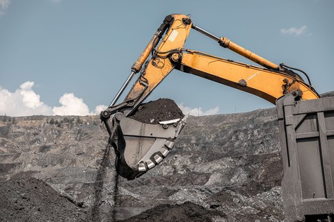 Большой карьерный экскаватор. Большой желтый горный экскаватор на рабочем месте. Загрузка угля в кузов самосвала. Карьерный экскаватор, горная техника для погрузки породы. Добыча полезных ископаемых.