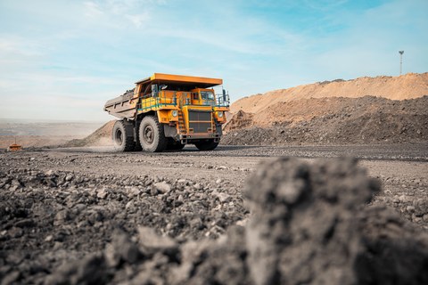 Большой карьерный самосвал. Большой желтый горный грузовик на рабочей площадке. Загрузка угля в кузов самосвала. Добыча полезных ископаемых. Карьерная техника для транспортировки угля из разреза.