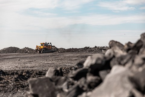 Большой карьерный самосвал. Большой желтый горный грузовик на рабочей площадке. Загрузка угля в кузов самосвала. Добыча полезных ископаемых. Карьерная техника для транспортировки угля из разреза.